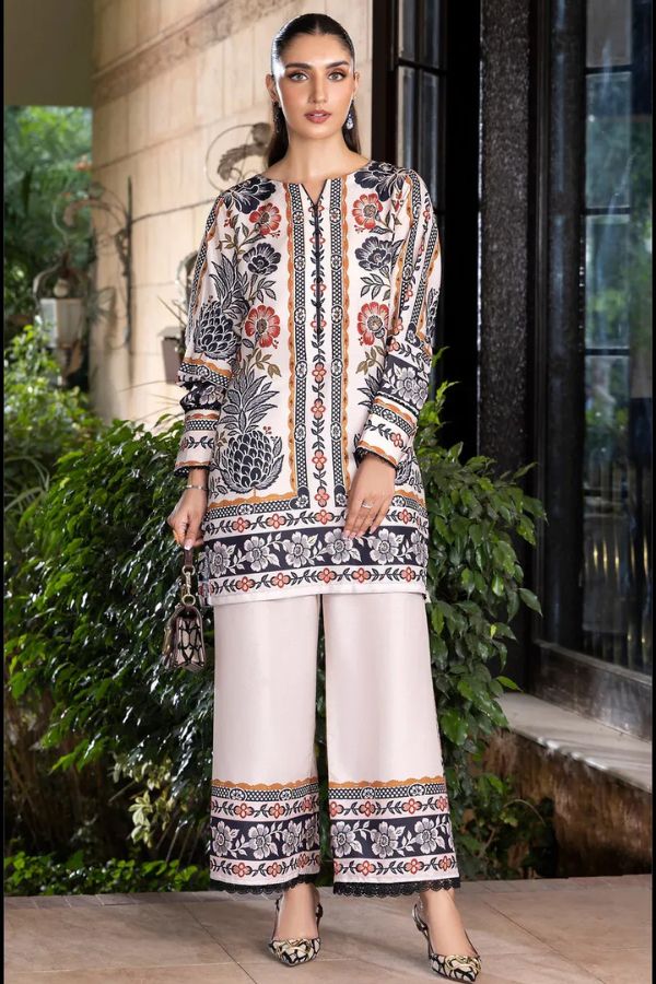 Woman wearing a patterned outfit with white pants standing outdoors.