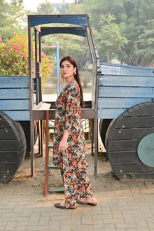 Woman in a floral dress standing next to a blue cart with greenery in the background