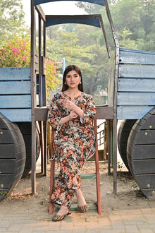 Woman in a floral dress standing in front of a blue metal structure with greenery in the background