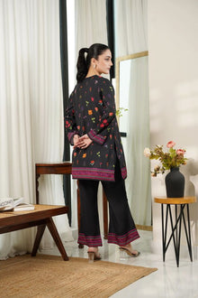 Woman wearing a black floral patterned outfit in a room with white curtains and a vase of flowers.