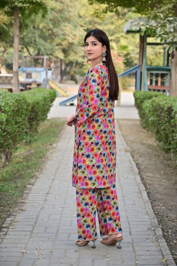 Woman in a colorful floral outfit walking on a path with greenery around.