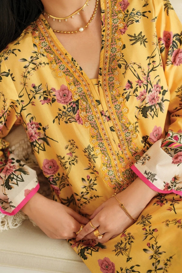 Yellow floral dress with intricate patterns and jewelry on a neutral background