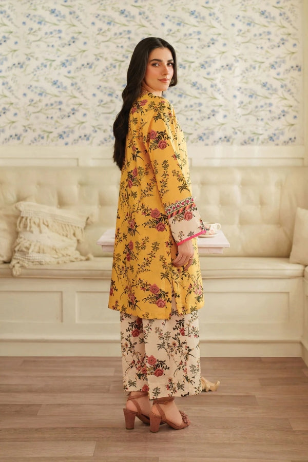 Woman in a yellow floral outfit standing in a room with floral wallpaper.