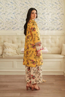 Woman in a yellow floral outfit standing in a room with floral wallpaper.