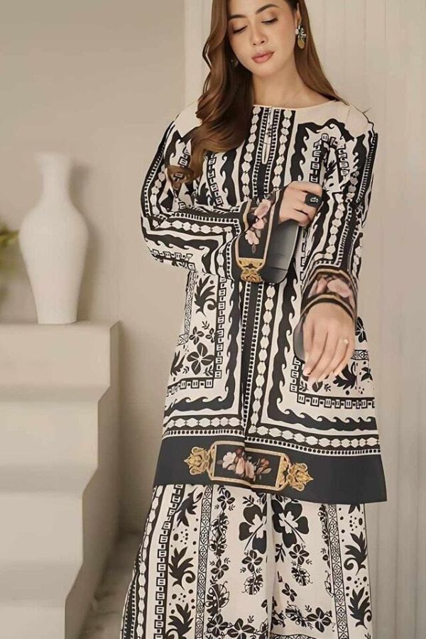 Woman wearing a black and white patterned dress holding a phone.