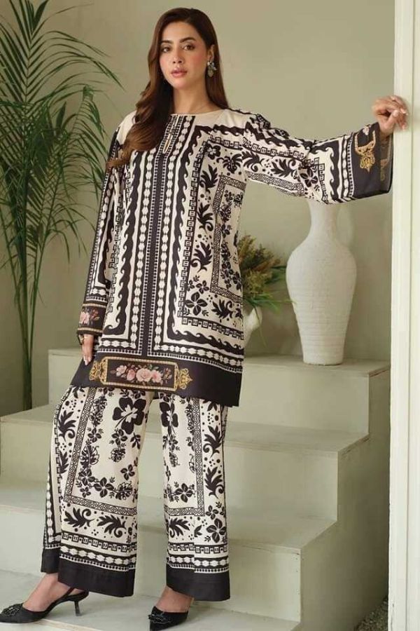 Woman wearing a black and white patterned outfit standing indoors with decorative elements.