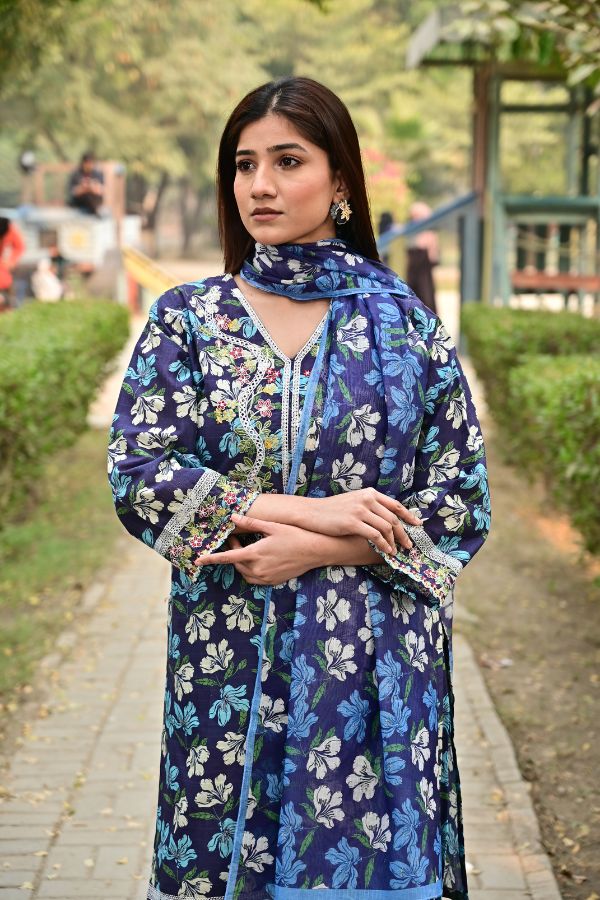 Woman wearing a blue floral dress standing outdoors.