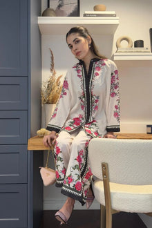 Woman in a floral dress sitting on a chair in a room with shelves and decor.