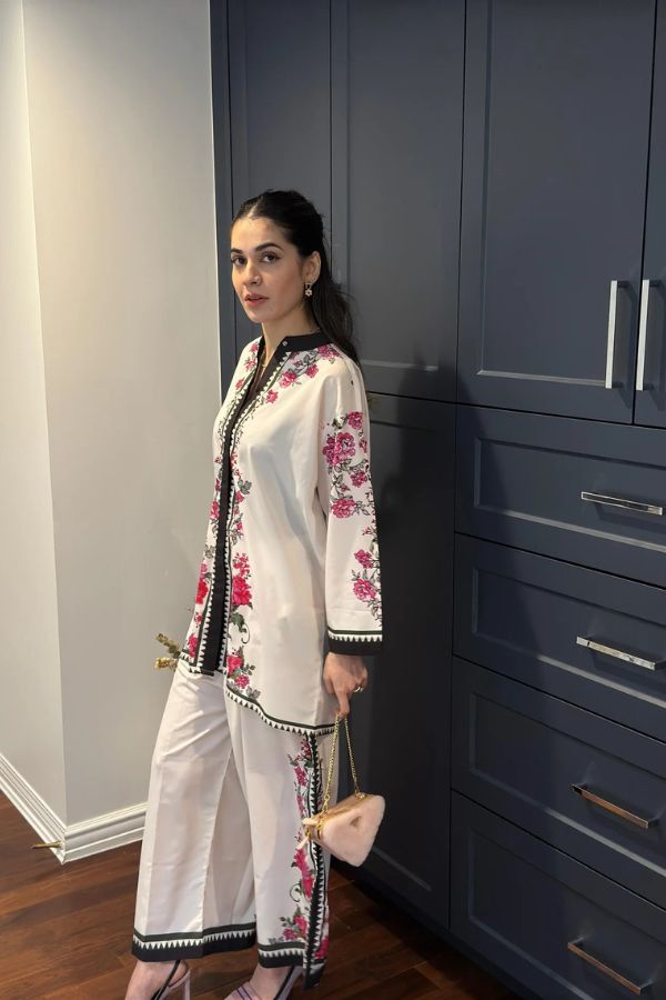 Woman in a floral outfit standing against a dark blue wardrobe.