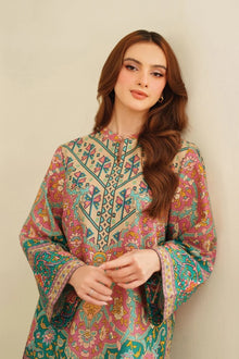 Woman wearing a colorful embroidered dress against a plain background