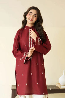 Woman wearing a maroon embroidered dress against a plain background