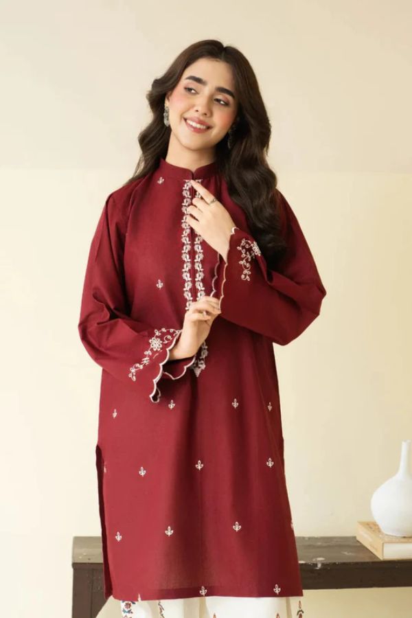 Woman wearing a maroon embroidered dress against a plain background
