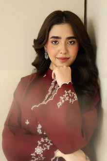 Woman wearing a maroon embroidered outfit against a neutral background