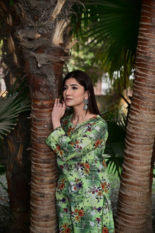 Woman in a green floral dress standing between palm trees
