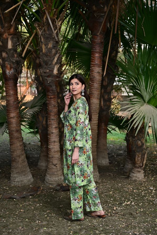 Woman in a green floral outfit standing among palm trees