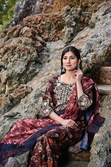 Woman in a floral dress sitting on stone steps with a natural rock background