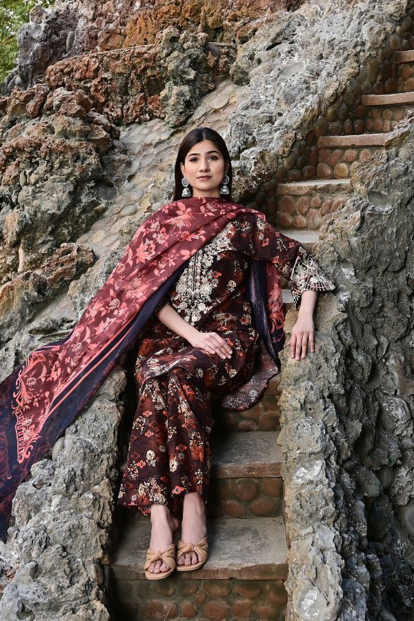 Woman in a floral saree sitting on stone steps with a natural rock background