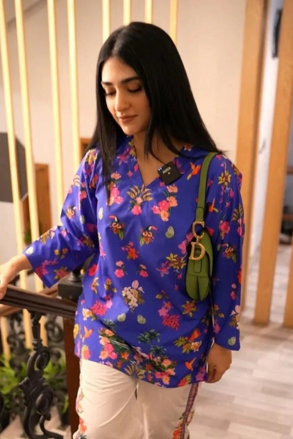 Woman wearing a blue floral blouse with a green bag indoors.