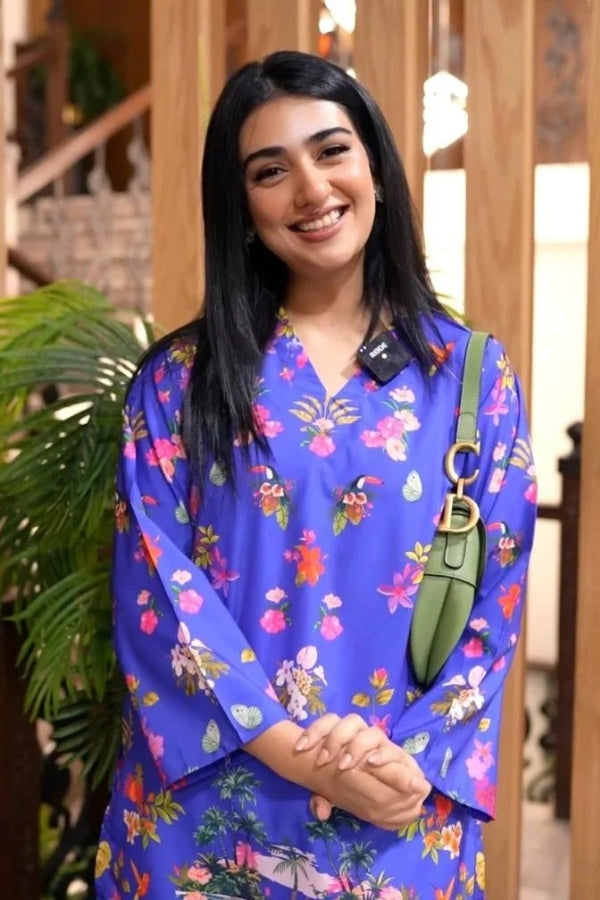 Woman wearing a blue floral dress with a green bag indoors