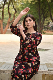 Woman in a floral dress sitting outdoors with trees in the background