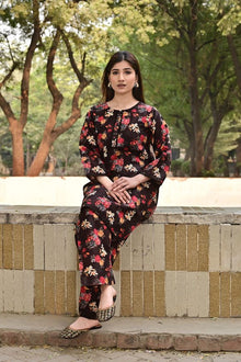 Woman in a floral outfit sitting outdoors with trees in the background