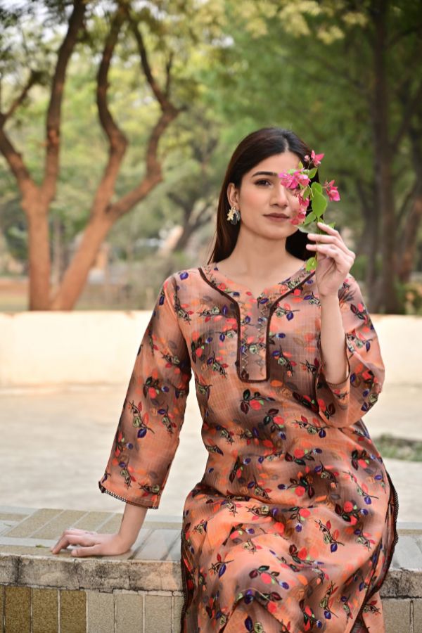 Woman in a floral dress sitting outdoors with trees in the background
