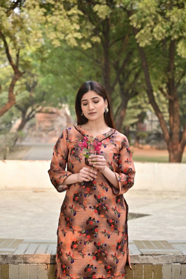 Woman in a floral dress standing outdoors with trees in the background