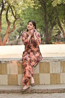 Woman in a floral outfit sitting on a stone bench with trees in the background