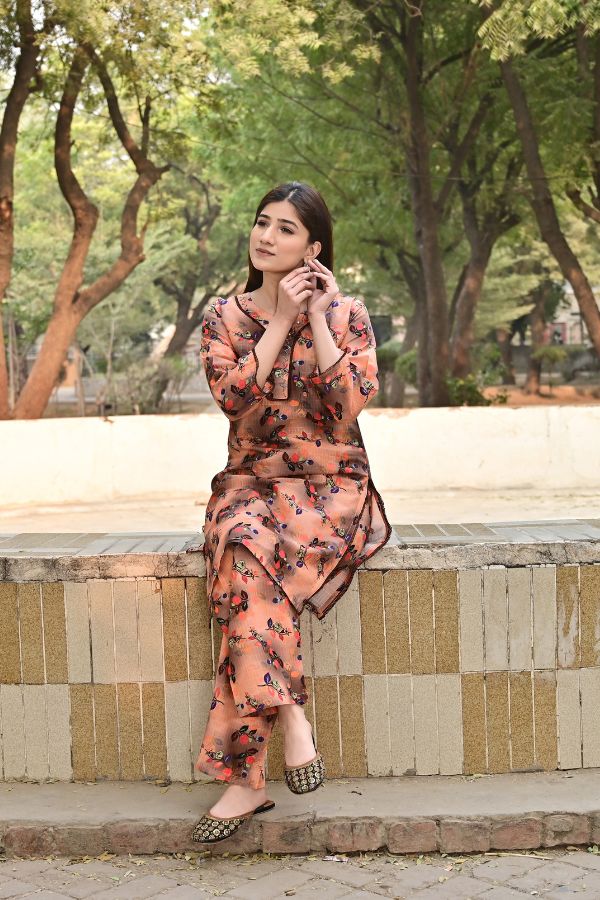 Woman in a floral outfit sitting on a stone bench with trees in the background