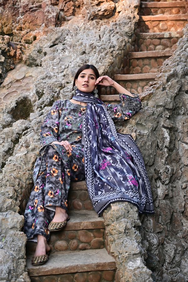 Woman in a floral outfit sitting on stone steps with a textured wall background