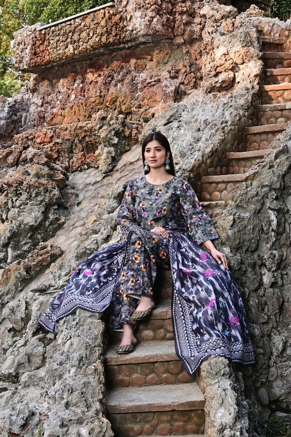Woman in a floral dress sitting on stone steps with a stone wall background