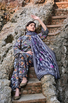 Woman in a floral outfit sitting on stone steps with a textured wall background