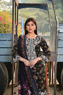 Woman in a floral dress standing in front of a wooden structure with greenery in the background