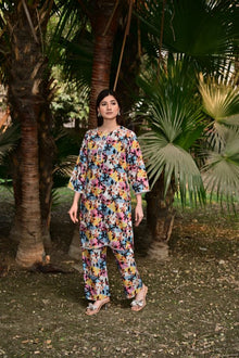 Woman in a floral outfit standing among palm trees