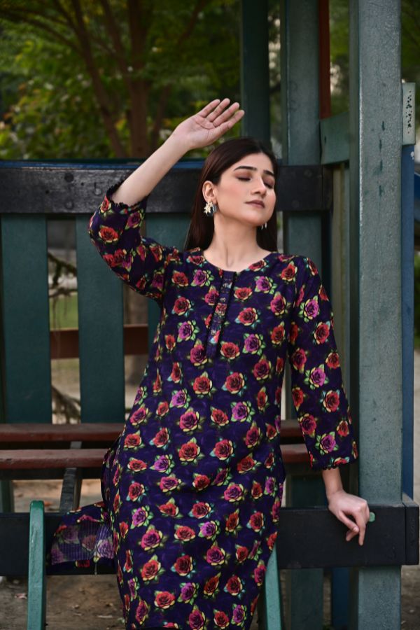 Woman wearing a dark blue floral dress sitting on a bench outdoors.